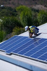 Close up of a technician installing solar panels on a tin roof.