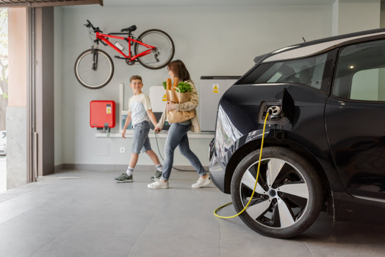 Electric vehicle charging station in private home with mother and son walking by